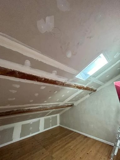 Combles aménagés avec fenêtre de toit et parquet posé