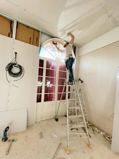 Peinture d'un plafond en cours, artisan sur escabeau